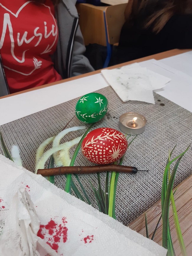 Na ławce leżą pisanki woskowe i pisak