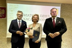 Dwóch mężczyzn i kobieta z kwiatami oraz teczką w rękach stoją