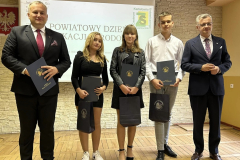 Starosta i Wicestarosta Powiatu Piotrkowskiego wraz z uczniami pozują na stojąco do zdjęcia