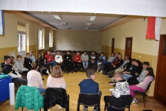 Uczniowie siedzą na krzesłach w tle ściana