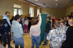 Uczniowie stoją rozdzieleni kotarą, w tle okna