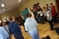 Uczniowie stoją rozdzieleni kotarą, w tle ściana