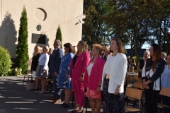 Nauczyciele stoją, w tle ściana, drzewa