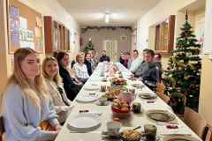 Uczniowie wraz z wychowawcą siedzą przy stole z potrawami wigilijnymi