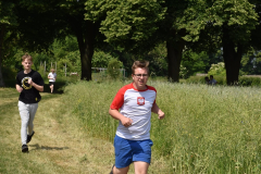 Młodzież biegnie dróżką obok zboża, w tle drzewa