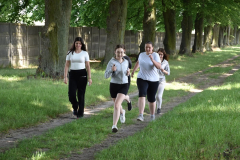 Grupa dziewczyn biegnie wśród drzew