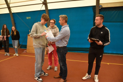 Dyrektor szkoły wręcza uczniowi dyplom, w tle inne osoby