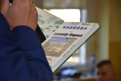 Zdjęcie przedstawia rękę z mikrofonem i książkę