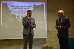 Na scenie stoi Wicestarosta Powiatu Piotrkowskiego i kierownik szkolenia praktycznego, w tle zdjęcie budynku szkoły