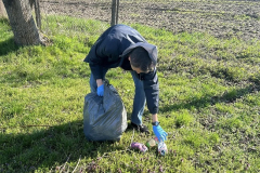 Uczeń podnosi śmieci z trawy