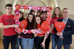 Uczniowie i dyrektor stoją w rękach trzymają czerwone balony