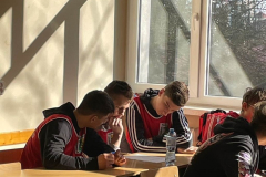 Uczniowie siedzą pochyleni na kartkami