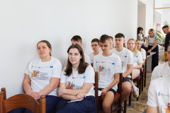 Młodzież w białych koszulkach siedzi na krzesłach