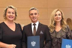 Mężczyzna stoi w środku, po bokach stoją kobiety