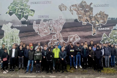 Uczestnicy wycieczki pozują do zdjęcia na tle mapy