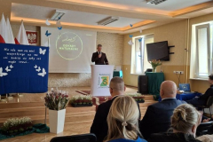 Dyrektor szkoły stoi z mikrofonem w ręku na scenie