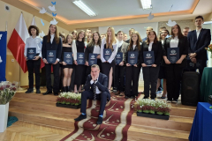 Uczniowie stoją, nauczyciel siedzi na schodach