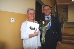 Dyrektor szkoły wręcza kwiaty Przewodniczącej Rady Rodziców kwiaty, w tle ściana