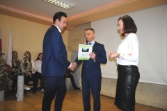 Dyrektor szkoły wraz z wychowawczynią wręczają świadectwo ukończenia szkoły uczniowi